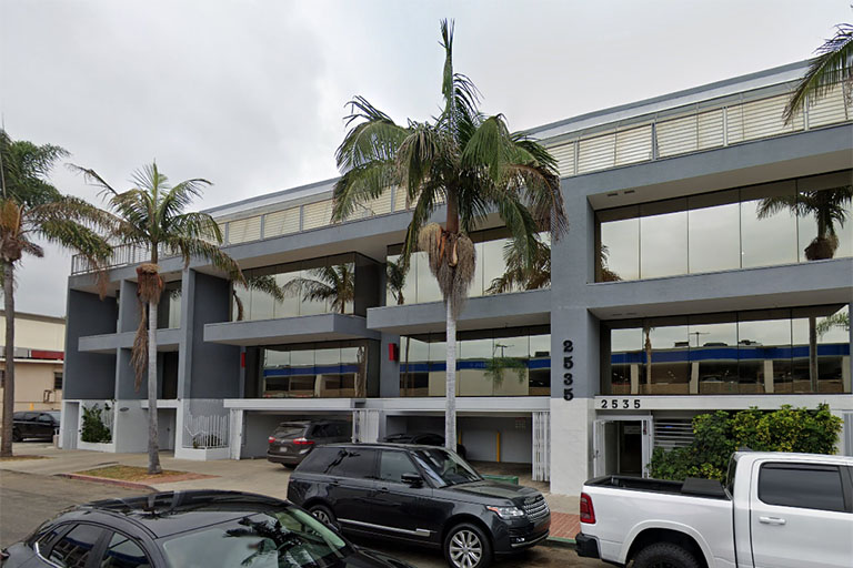 Street view of a gray, two-story office building at 2535 Kettner Blvd in San Diego, CA, with palm trees and parked cars in front.